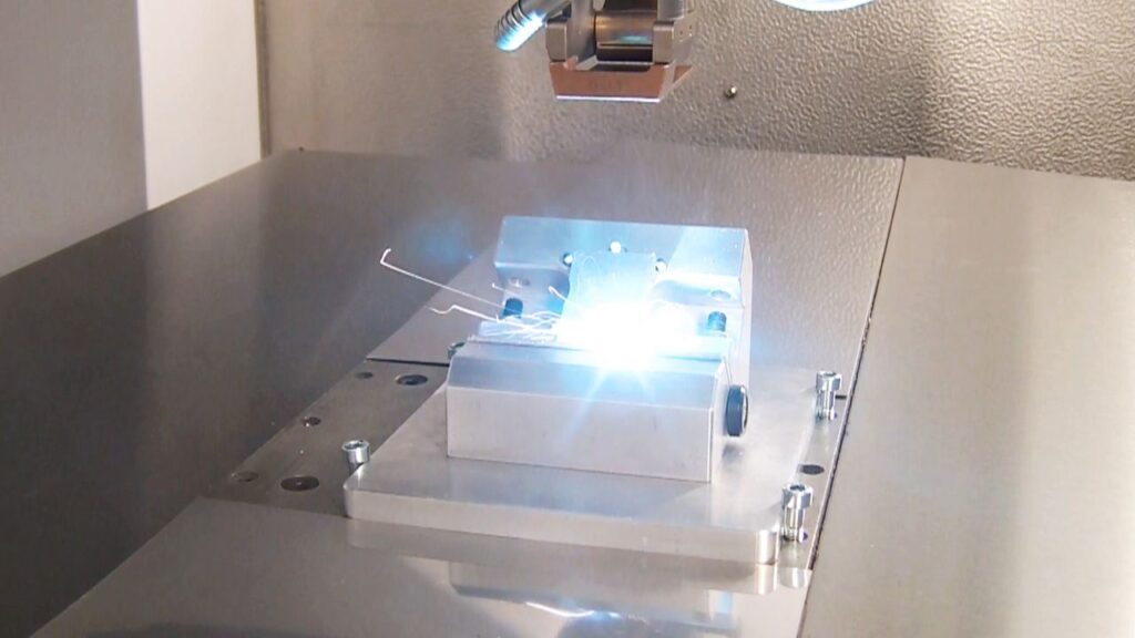 Mikroschweißen mit Lasertechnik – SLT – Edwin Schmitt Lasertechnik Aktiver Laserschweißprozess bei Edwin Schmitt Lasertechnik: Präzises Mikroschweißen eines Metallbauteils mit minimaler Wärmeeinwirkung.